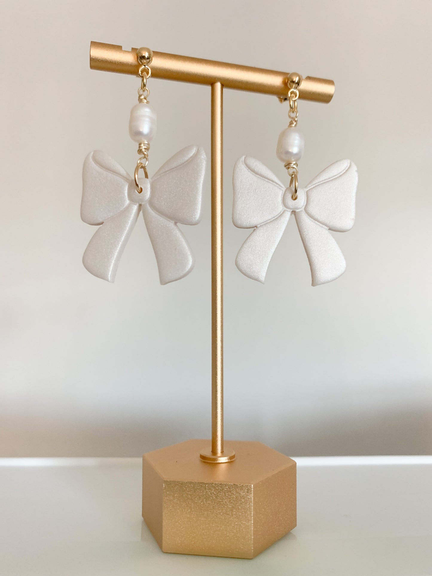 A pair of handcrafted polymer clay earrings featuring 18K gold plated earring posts and a mini pearl