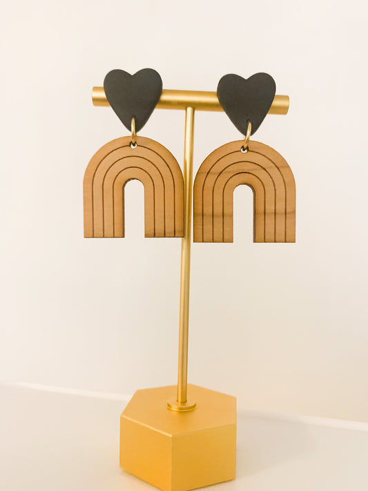 A pair of handmade polymer clay earrings featuring a wooden rainbow and gold plated earring posts.