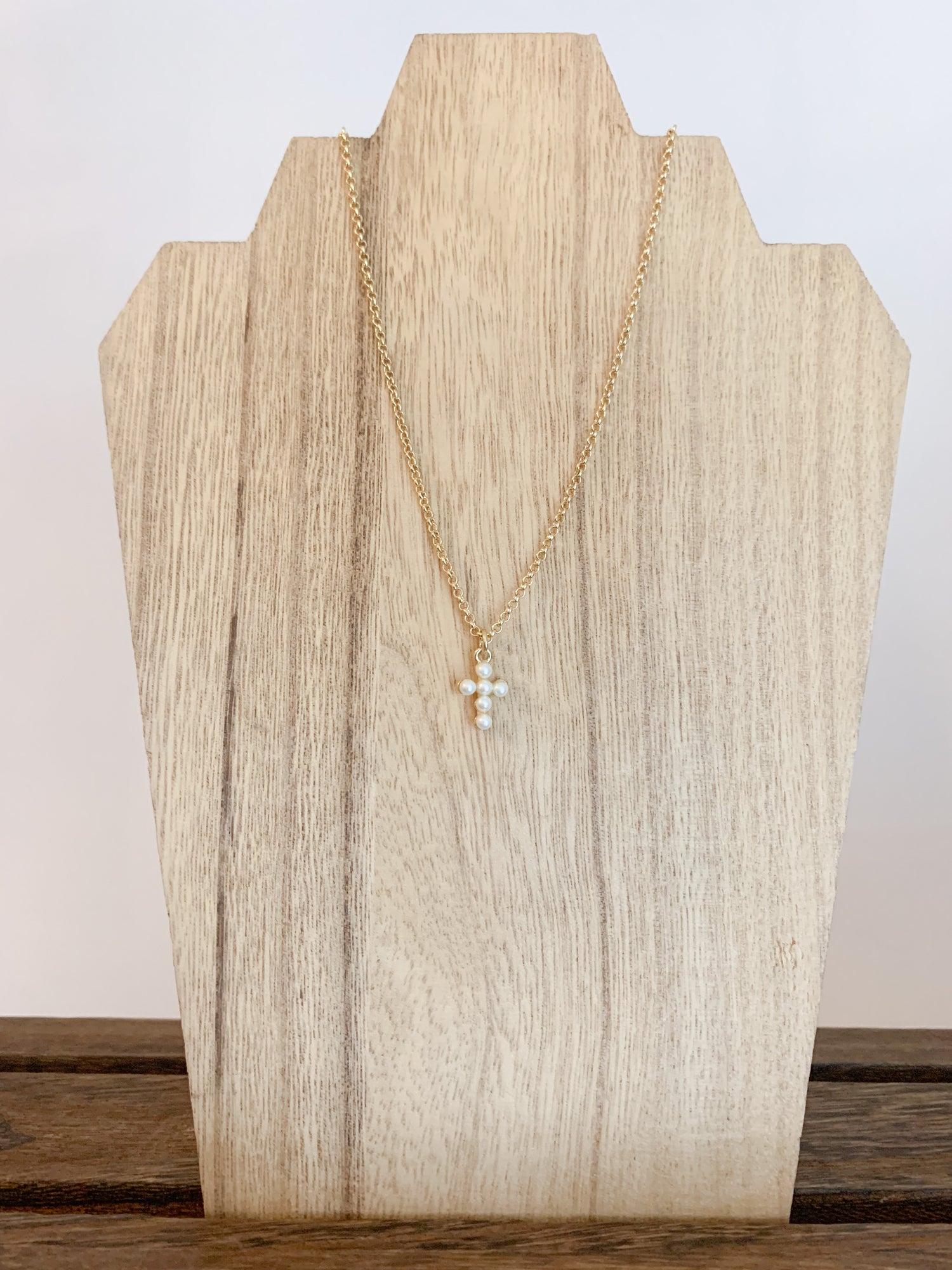 18k gold plated pearl cross necklace on a white background, with the cross centerpiece in focus. A beautiful and elegant jewelry piece to add to your collection.