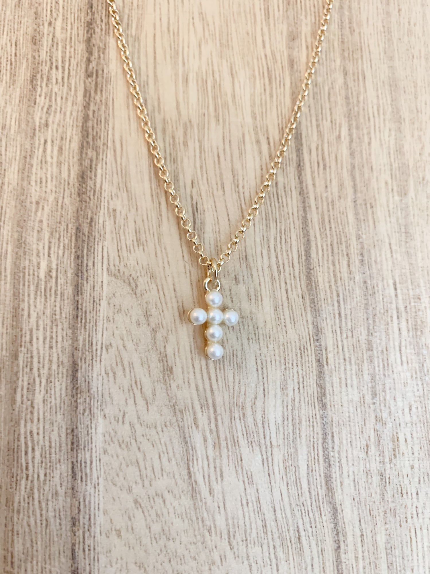 18k gold plated pearl cross necklace on a white background, with the cross centerpiece in focus. A beautiful and elegant jewelry piece to add to your collection.